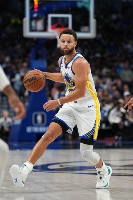 Koszykarz Stephen Curry kozłuje piłkę podczas meczu na boisku NBA.